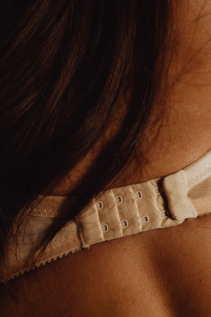 Intimate close-up of a woman's back showcasing elegant lingerie and brunette hair.